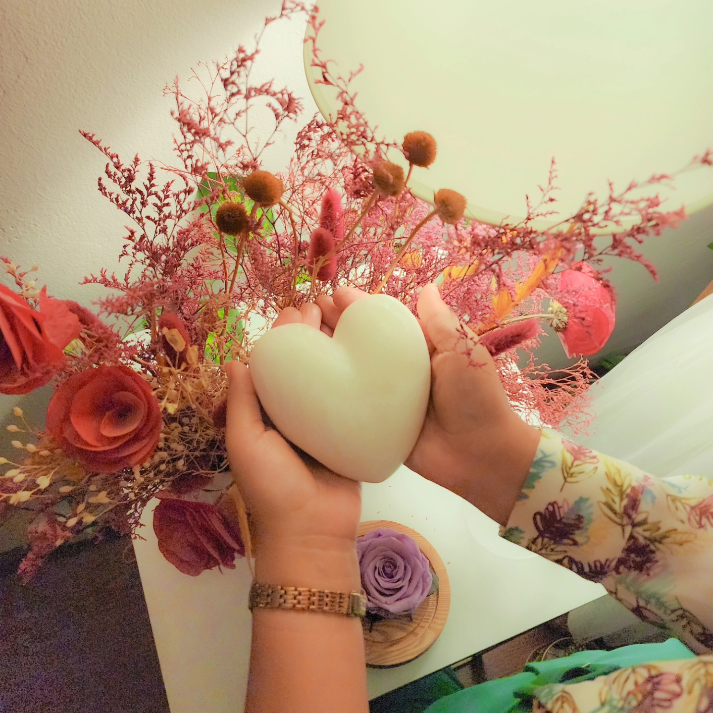 Manos sosteniendo un corazón entre flores